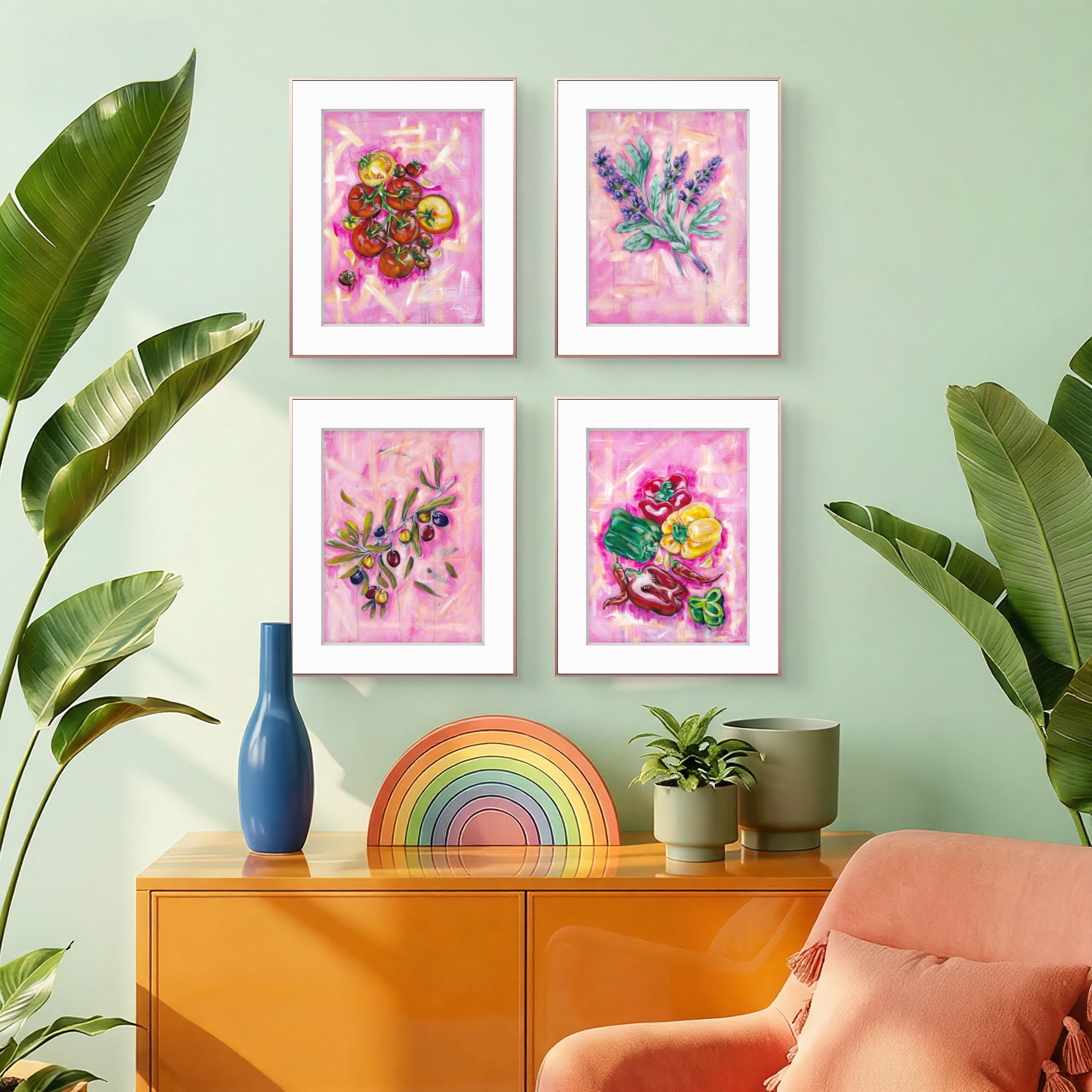 Four framed Luna Burlo kitchen artworks on a wall with a colorful vase, rainbow decoration, and plant in the foreground.
