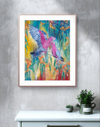 Framed canvas fine art print of a colorful painting of a native Australian galah birds and eucalyptus flowers on a grey wall above a white cabinet with plants. Blue, yellow, red background, with vertical or portrait style orientation. Artist: Luna Burlo, Melbourne, Australia