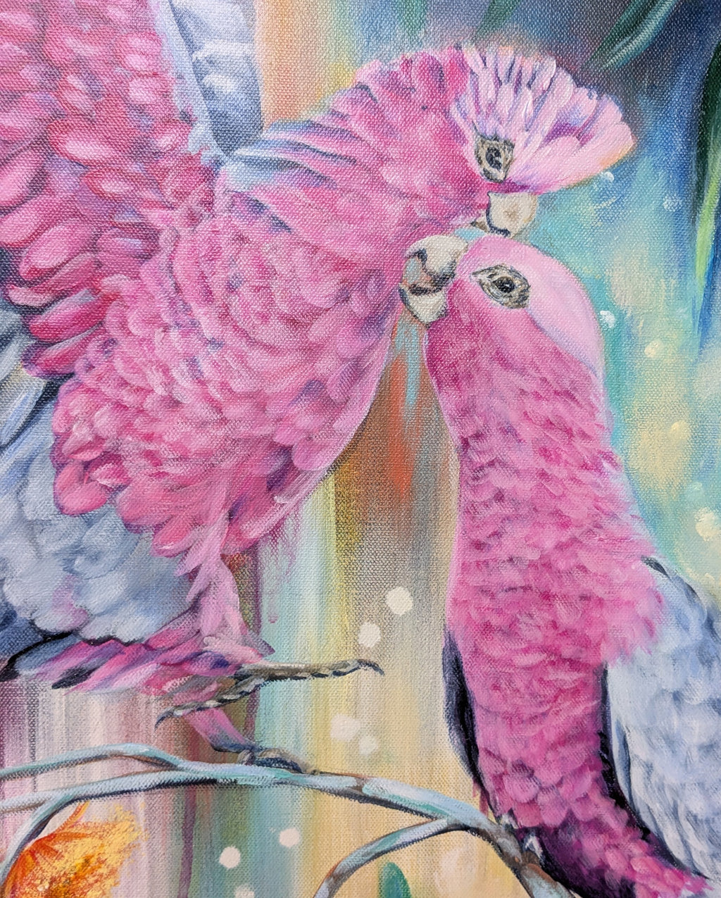 Large painting of two Australian pink galahs perched on a native plant, eucalyptus, branch with a colorful blue, gold, and orange background. Artist, Luna Burlo, Melbourne, Australia