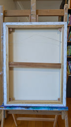 Wooden art easel with a blank canvas on a wooden floor.