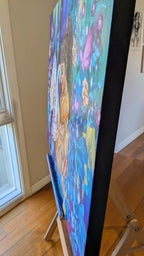 Colorful blue painting by Melbourne, Australia artist, Luna Burlo, sits on an easel in a room with wooden flooring and a window.