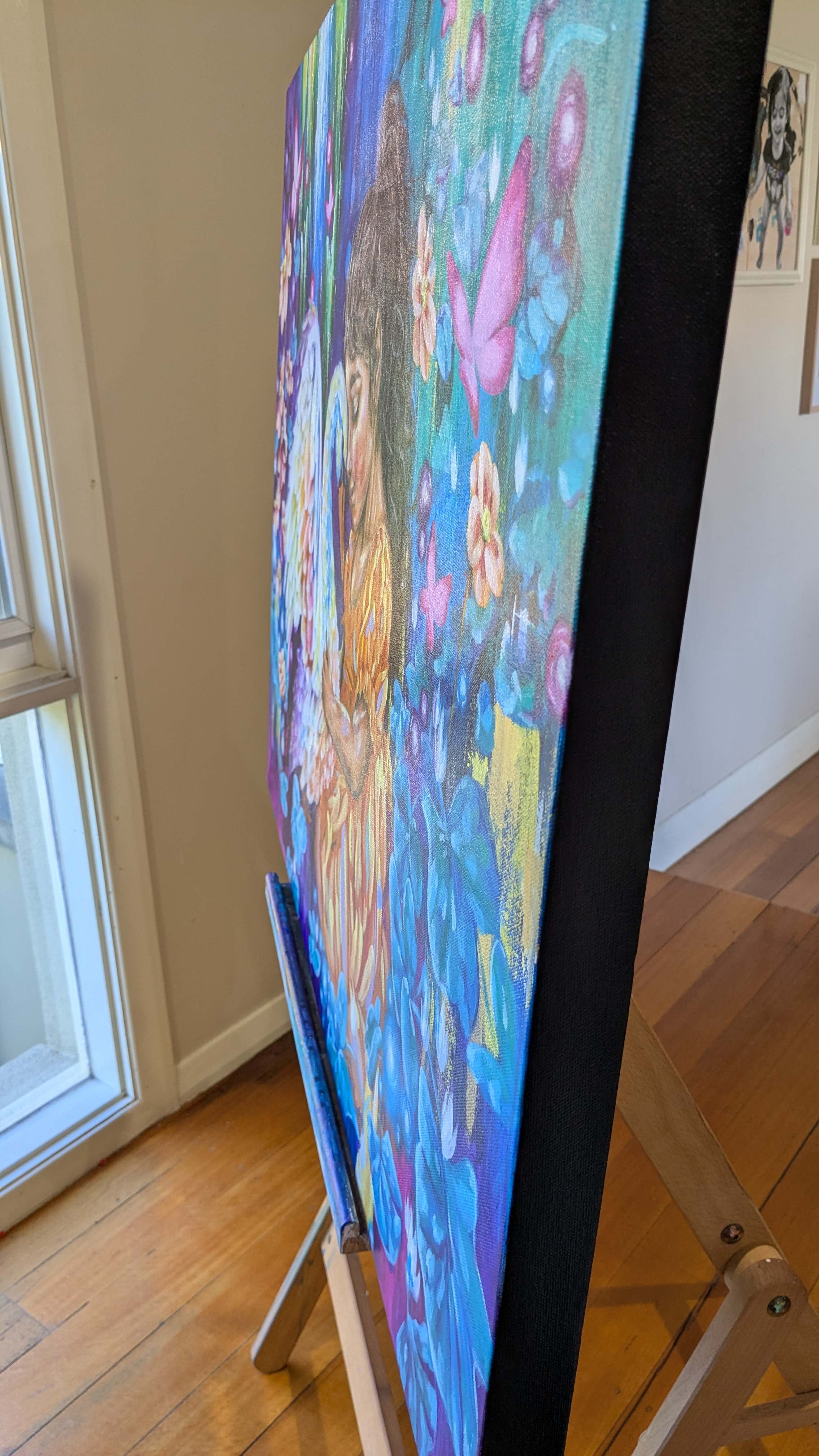 Colorful blue painting by Melbourne, Australia artist, Luna Burlo, sits on an easel in a room with wooden flooring and a window.