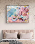 Framed light pink and blue painting or fine art print of peony and billy button  flowers and a teacup above a bed with floral wallpaper. Art by Luna Burlo, Melbourne, Australia