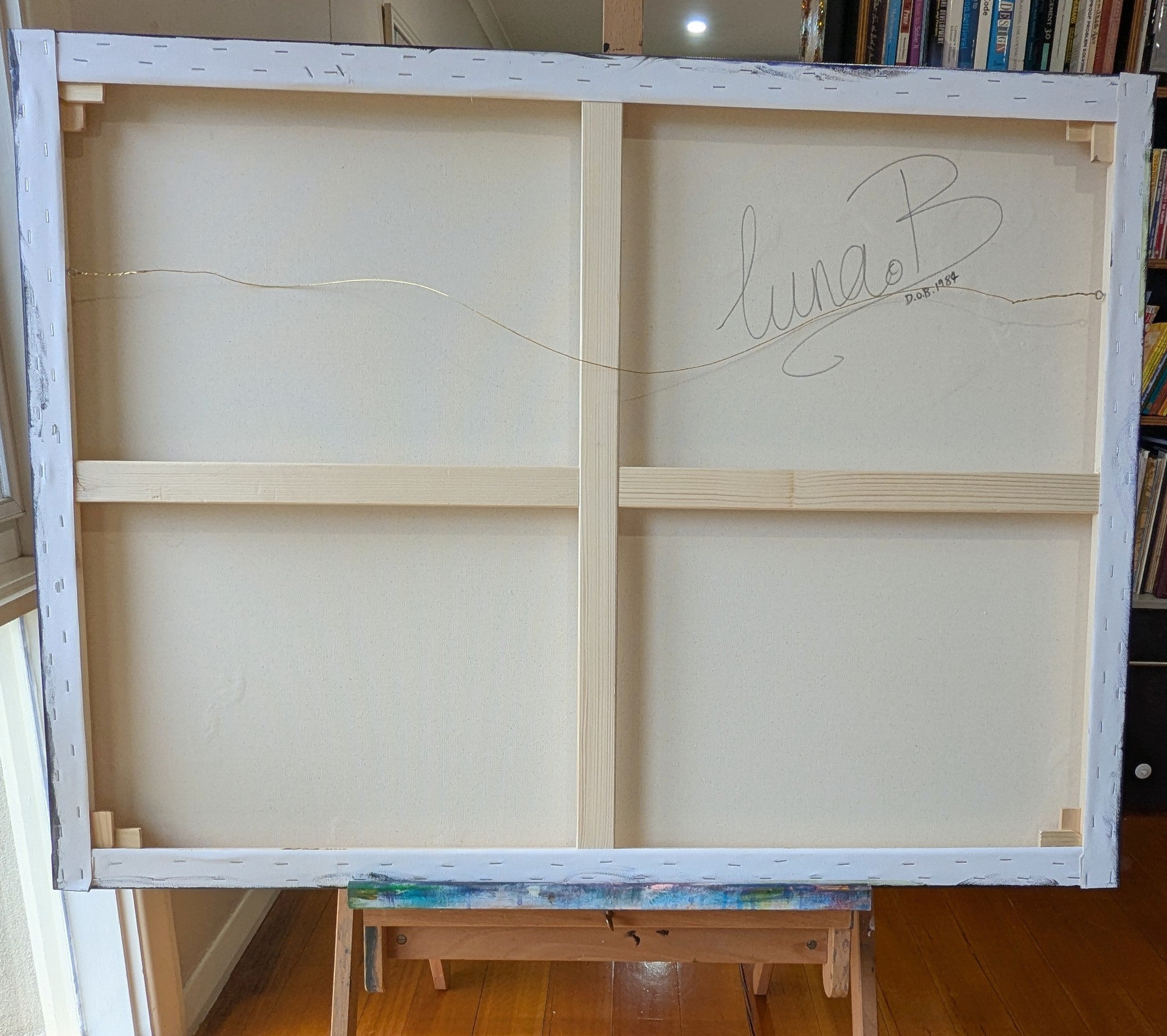 Large white canvas with a signature on an easel in a room. ainting "The Wren-ovated Bird Bath" by artist, Luna Burlo, Australia