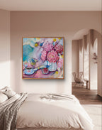 Colorful pastel blue and pink floral fine art canvas print of a painting on a cream wall above a bed in a bedroom. The painting is square and features pink peonies, and Native Australian birds (fairy wrens) and flowers (billy buttons). Artist: Luna Burlo, Melbourne, Australia