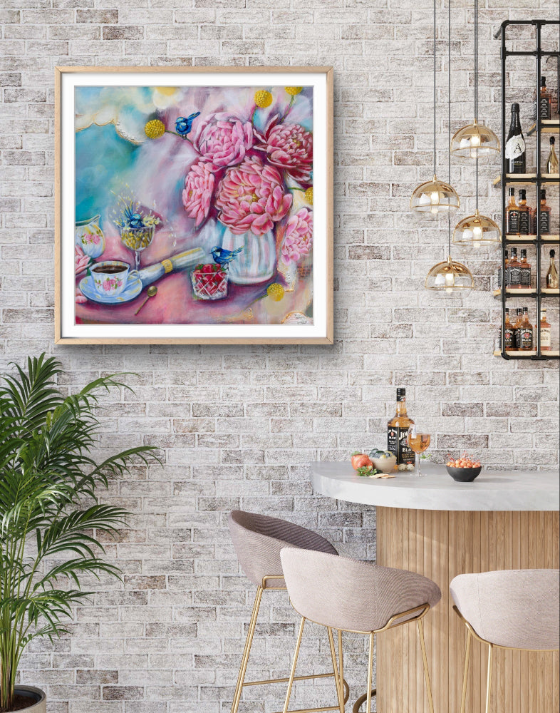 Framed fine art canvas print of a square painting of flowers and fairy wrens on a wall above a cafe bar with stools. Art by Luna Burlo, Melbourne, Australia